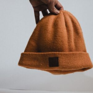 a hand holding a brown hat on top of a white surface